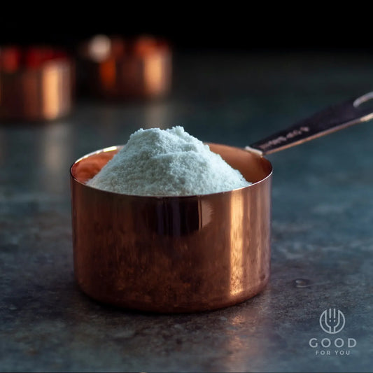 Copper measuring cup filled with white flour on a dark stone surface